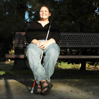 A blind girl sitting on a bench.