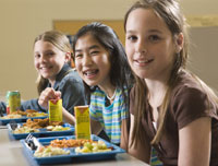 Three girls having lunch in a cafeteria.