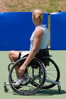 Girl in a wheelchair on a tennis court.