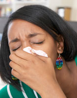A girl coughing into a tissue.