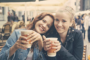 Two friends drinking warm beverages.