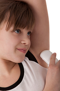 Young girl applying deodorant.