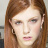 A surly looking girl with auburn hair.