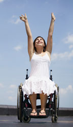 Girl in a wheelchair with her arms in the air.