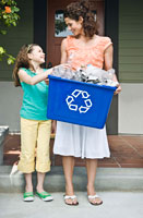 A mother and daughter carrying a recycling bin.
