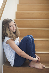 A girl sitting at the bottom of a straircase.