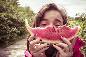 A girl eating a slice of watermellon.