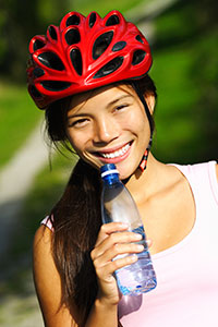 A smiling girl wearing a helmet and holding a water bottle.