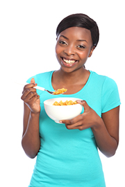 Photo of a teenage girl eating a bowl of cereal.