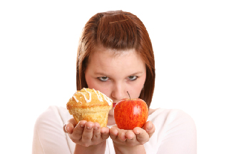 Photo of a teen girl holding an apple and a muffin.