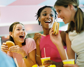 Photo of teenage girls eating at a fast food restaurant.