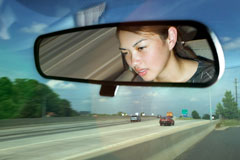 Girl's face in a rearview mirror.