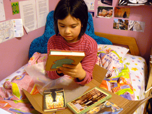 Adora Svitak on her bed with a lot of books