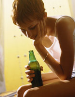 A sad girl holding a beer bottle.